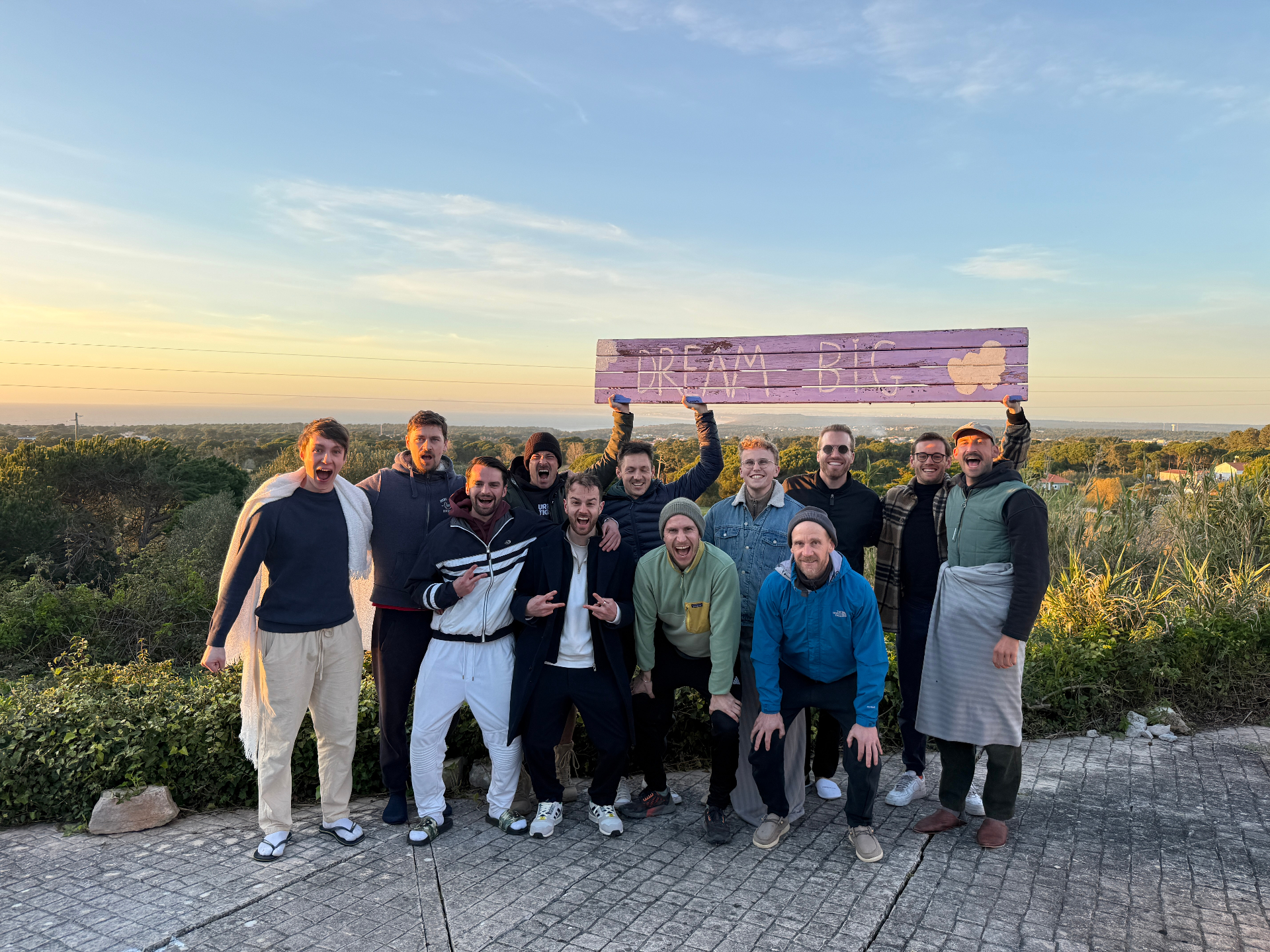 Gruppe von Männern bei Sonnenuntergang mit Dream Big Schild